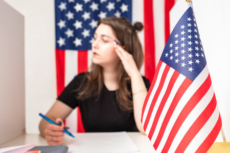 Filling out a ballot for voting in US elections. A woman sits next to an American flag and makes...