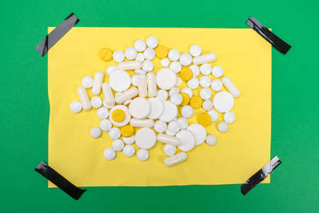The tablets are on a yellow sheet of paper with black adhesive tape. Prescribing medications by a doctor. Treatment regimen. Follow the doctor's instructions.の写真素材