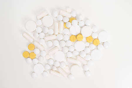 A pile of pills and pills on a white table. Medical care. Medical treatment of diseases. Pharmacological background. Development of new drugs.の写真素材