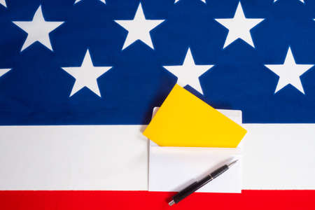 Letter and pen on the background of a fragment of the American flag. Correspondence with American officials. Mail from the USA. Bulletin on the election of the American President.の写真素材