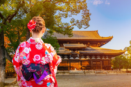 Japanese girl next to a Buddhist temple. A Japanese woman visits the sights of Kyoto on a Sunny day. Architecture Of Japan. Autumn in Japan. National Japanese costume.のeditorial素材