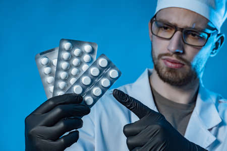 The doctor holds the tablets in his hands and points at them with his finger. Medical purpose. The doctor prescribes medicines to the patient. Tablets to eliminate the disease.の写真素材