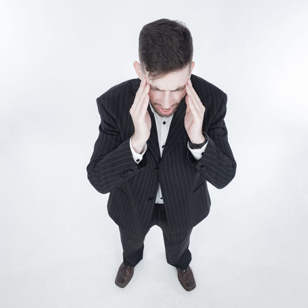 The man in the suit is holding his head.A man with a headache is photographed from above. The man...