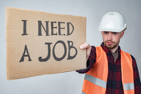 An unemployed Builder with a poster in his hands. The Builder is looking for work. Unemployment in...