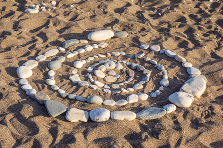 A spiral of stones is laid out on the sand. Pictures of stones. Beach ornament. Natural background...