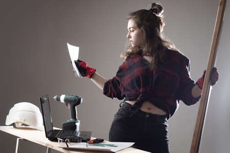 A female carpenter works in her workshop. A woman is engaged in woodworking. Craftswoman with a piercing. Work in a carpenter workshop.の写真素材