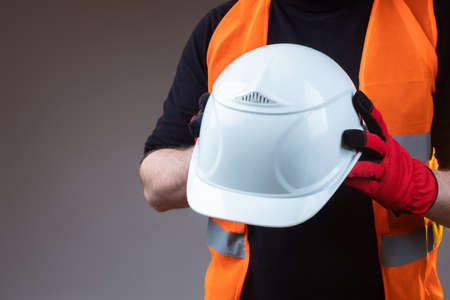 Construction helmet close-up. Construction concept. White construction helmet in the hands of a man. Safety. Labor protection of builders. Protective uniforms.の写真素材