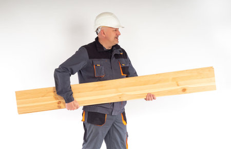 A construction worker carries wooden planks. Renovation, construction and concept of a house under...