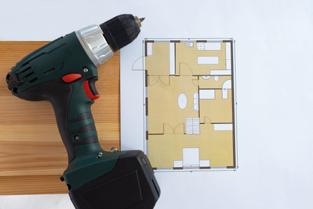 The battery-powered screwdriver is next to the apartment plan. Renovation of the apartment. Repair...