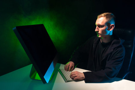 Programming. A man writes a computer program. A man at a computer on a black background with green...