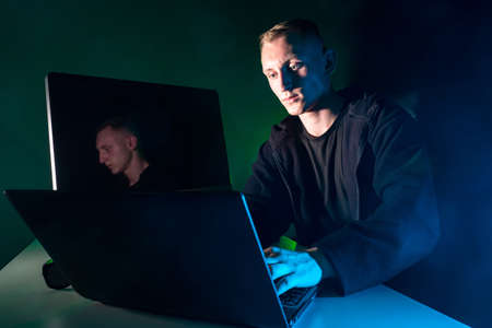A man performs urgent work on a laptop. Human and computer gadgets. Irregular working hours. Working on the computer at a later time.の写真素材