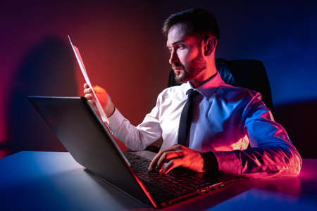 A man works on a laptop. A person composes a response to a business letter. The businessman conducts online correspondence with contractors. A man in business clothes at the computer.の写真素材