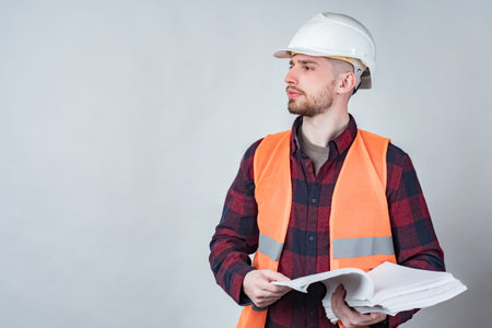 Foreman of the construction documents in hand. A man in a hard hat and reflective vest stands on a...