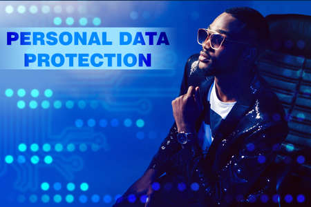 dark-skinned man is sitting in a chair on a blue background. The person next to the label about personal data protection. Business, technology, internet and network conceptの写真素材