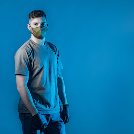 A man in a protective mask and gloves on a blue background. Protection from the virus. Security...