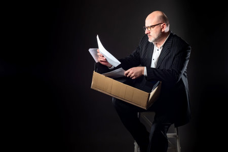 A man sits on a stool and looks through documents. Business failures. A person tries to find the...