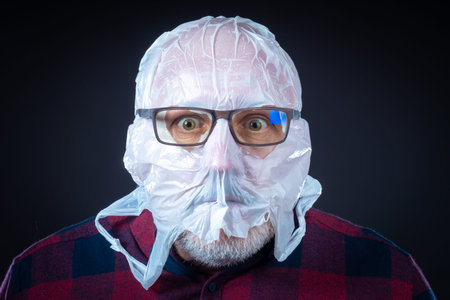 A plastic bag with eye slits on a person's head. The man put a bag and glasses on his head. Trying...