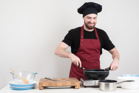 Happy chef. A man is happy to cook food. A man in a chef's uniform cooks food in a frying pan and...