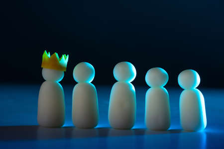 The concept of a collective with symbolic little men. A team of little men with a leader. The boss in the crown and his subordinates. White men on a dark background.の写真素材