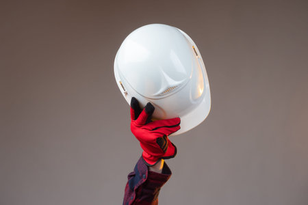 White construction helmet close-up. The man makes a greeting gesture with a white construction...