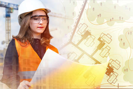 Cartography and geodesy. The girl works as a cartographer. A woman makes maps. A girl in a white helmet with drawings in her hands. A woman surveyor at a construction site.の写真素材