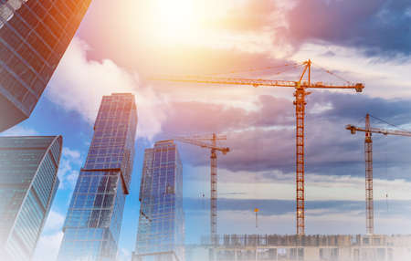 Urban construction. Architecture. Finished skyscrapers and cranes against the blue sky. Construction of new multi-storey buildings.の写真素材