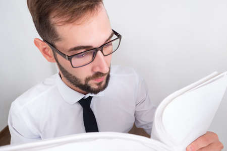 Man with documents in his hands. Bearded businessman with a bundle of papers in his hands. The lawyer looks through the documents. The auditor in glasses and a white shirt is photographed from above.の写真素材