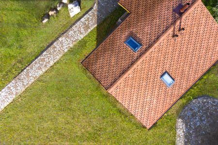 Roof of the cottage and the surrounding area with a quadrocopter. Roof of the house is covered with flexible soft tiles. The roof of the house with Windows and pipes. Construction of the building.の写真素材