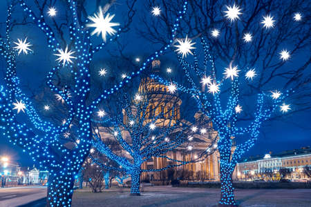 Christmas in Saint-Petersburg. St. Isaac Cathedral on the background of garlands. Street Christmas decorations in the evening. Winter holidays. Festive garlands on the trees in Saint Isaac Square.の写真素材