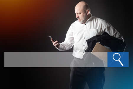 An empty search bar and a person who lost their job. A man looks at his smartphone and doesn't know what to do. Mass unemployment. The lack of vacancies. Fear of losing your job. Crisis. Ruin.の写真素材