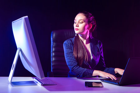 Business woman. A woman in a business suit at a table with computer equipment. A beautiful woman...