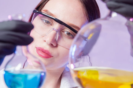 Portrait of a female chemist. The girl face in protective glasses next to the flasks. The technician...