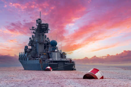 Moored ship against the background of dawn. Warship on the water against a beautiful sky. Military fleet. Naval forces at dawn. The ship and the buoys on a background of pink sky.の写真素材