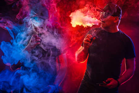 The concept of vaping. A man in a black baseball cap is Smoking an electronic cigarette. People in clouds of e-cigarette smoke. Bright collage about VAPE Smoking.の写真素材