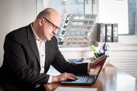 A businessman looks at the necessary information on the Internet. The man writes the customer an...