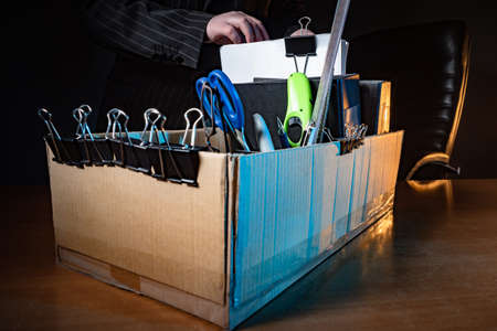 Symbol of leaving the workplace. Cardboard box with things from work. Dismissal. Termination of the company. A person is preparing to leave work. Staff reduction. Economic crisis.の写真素材
