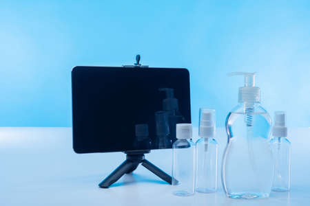 Bottles of disinfectants and an electronic tablet stand on the table. Cleaning of the equipment. Surface disinfection. Elimination of viruses and bacteria using disinfectant solutions.の写真素材