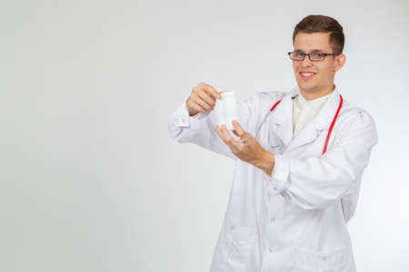 The concept of probiotics. A young smiling doctor with bottles of probiotic drink. Medical recommendations. Medical advice. Friendly doctor on a white background. Place for text.の写真素材