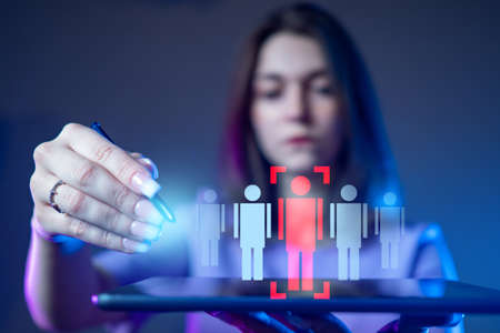 A girl with a tablet in her hands chooses one person from several. Personnel decision. Personnel manager. Employment. Dismissal. Personnel policy of the company.の写真素材