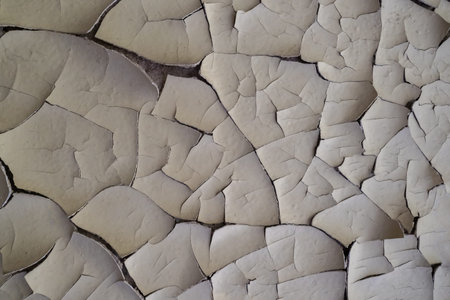 Cracked gray paint. Old paint on the wall. Light construction background. Cracks in the paint....