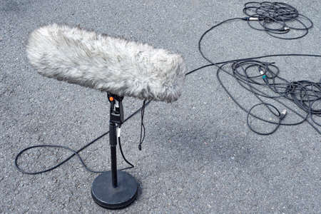 Windproof. Microphone in wind protection. Large street microphone in windproof fur. Professional equipment for video operators. Microphone stands asphalt. Concept - selling professional microphonesの写真素材