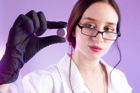 Vaccine. Virologist holds a pill in his hands. Woman virologist. Tablet in hand of a laboratory assistant. Concept - pill is a vaccine against virus. Cure for pandemic. Research on cures for pandemicの写真素材