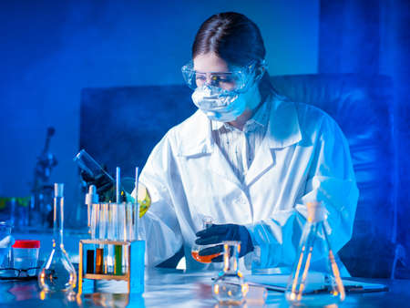 Lab technician works with hazardous chemicals. Virologist studies the tests. Concept - laboratory isledovaniyu viruses. Creation of viruses. Test tubes on the laboratory table. Examines test tubes.の写真素材