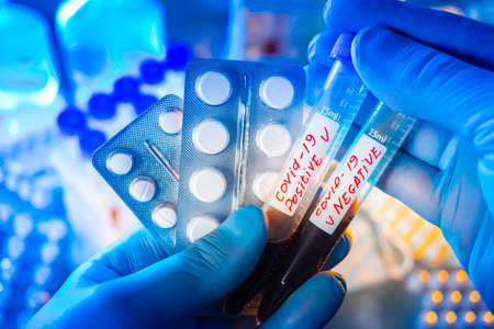 Lab technician holds test tubes with covid. Pills next to blood samples. Concept - creation of drugs...