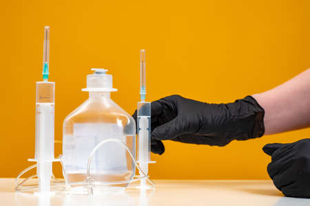 hand with gloves holding dropper. Syringes and droppers on a tabletop. Concept - the struggle with the consequences of the epidemic. Pandemic treatment. Reducing the effects of fever.の写真素材