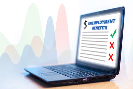 Inscription unemployment benefit on a laptop. Charts symbolize rising unemployment. Concept - site for receiving unemployment benefit. Increased compensation claims. Laptop on a light background.の写真素材