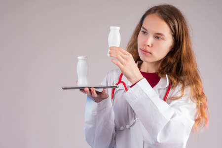 Probiotics and prebiotics. The doctor examines a bottle of fortified yogurt. Medical recommendations for nutrition. Healthy food. Probiotic-rich foods. Prevention of dysbiosis.の写真素材