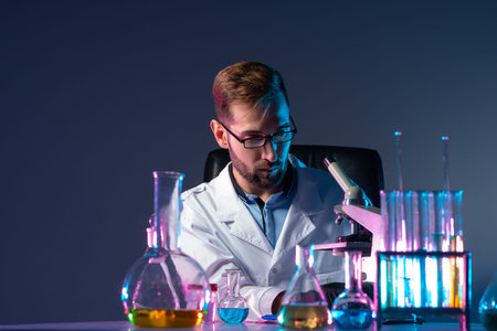 Scientist on the background of test tubes and a microscope. The chemist is sitting in the lab. A...