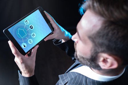 Application smart home system in a man in tablet. Human holds a gadget on a dark background. It...