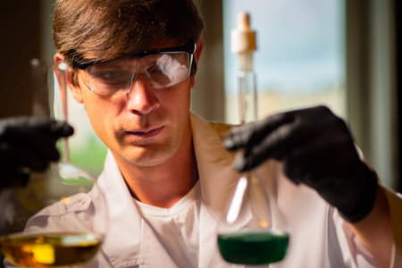 Pharmacological laboratory. Guy laboratory assistant examines liquid in test tubes. Lab assistant...